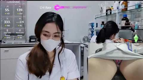 Media: Video of an Asian woman in a lab coat, face mask, and gloves, analyzing a monitor showing vital signs. In the background, another woman is bent over, exposing her buttocks.