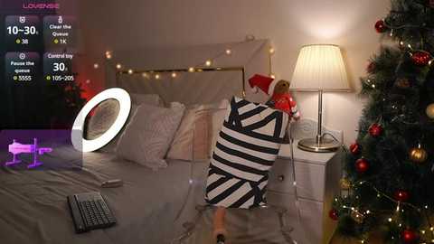 Media: Video of a cozy bedroom with a white bed, Christmas tree, string lights, a lamp, and a plush toy.