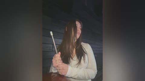 Media: Video of a woman with long brown hair, laughing joyfully while holding a white plastic spoon, against a dark, blurry background.