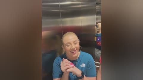 Media: A video of a smiling woman with blonde hair in a blue uniform, standing in a kitchen with stainless steel appliances and colorful containers in the background.