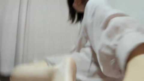 Media: A blurred video of a person in a white robe, bending over, with a wooden object in the foreground, suggesting a medical setting.