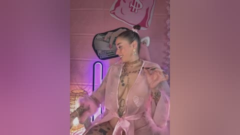 Media: Video of a tattooed woman in a sheer pink robe, holding a plate, against pink tiled walls with a neon sign and posters.