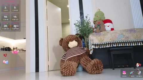 Media: Video of a plush brown teddy bear wearing a striped shirt, sitting in a modern, white-tiled room with a kitchen in the background.