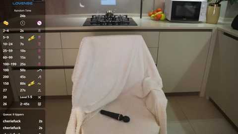 Media: Video of a kitchen countertop with a white towel-draped chair, a black microphone, and a microwave. The background features a stove, sink, and fruit bowl.