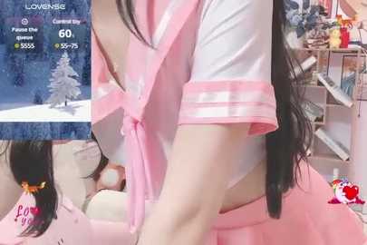 Media: Video of a young Asian woman in a pink sailor outfit, kneeling on a pink carpet, with a snowy background. Text overlay shows \"Love Live!\" and \"Poco's Uta,\" indicating a video game context.