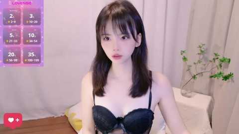 Media: Video of a young Asian woman with straight black hair, wearing black lace lingerie, seated indoors with a digital background showing social media metrics.