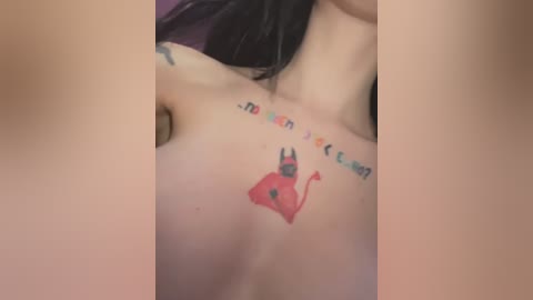 Media: A close-up video of a woman's upper back showing a colorful tattoo of a devil with a pitchfork, and a series of colorful letters spelling \"Satanic.\" The background is blurred and out of focus.