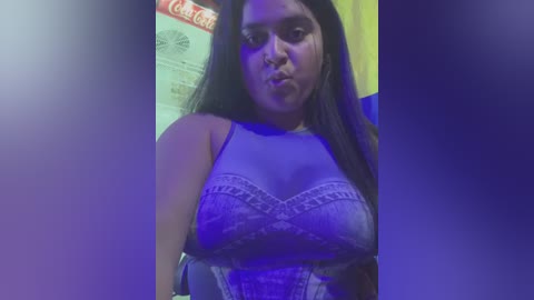 Media: A video of a young, light-skinned Latina woman with long black hair, wearing a revealing, lacy purple bra, pouting in a dimly lit room.