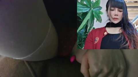 Media: A video featuring a close-up of a person's hand, with a background image of a woman in a red blazer and black choker, surrounded by large green leaves.