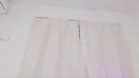 Media: A video of a plain, white curtain hanging from a window, slightly faded and wrinkled, against a white wall. The room is sparsely furnished, with a hint of an air conditioner on the left.