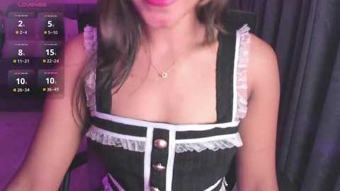 Video of a woman wearing a black and white maid outfit with lace trim, her breasts partially exposed, in a dimly lit room with a virtual game interface overlay.