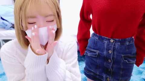 Media: A video juxtaposes a sick Asian woman in a white sweater and face mask, and a healthy woman in a red sweater and blue denim skirt.