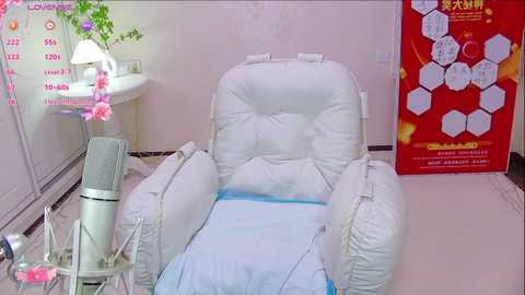 Media: Video of a white, plush recliner chair with blue cushion in a clinical room. Adjacent to the chair, a white medical bed with a white blanket. Red poster displaying medical information.