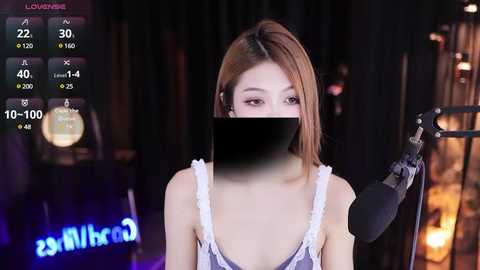 Media: Video of an Asian woman with long, straight brown hair, wearing a sleeveless dress, standing behind a microphone, blurred background with stage lights.