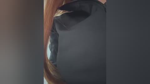 Media: A close-up video of a person with long, straight, reddish-brown hair, partially covered by a black motorcycle helmet. The background is blurred, focusing attention on the helmet's sleek, matte finish and the hair's texture.