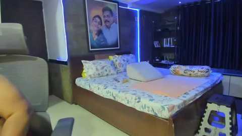 Video of a modern bedroom with a large bed adorned with floral bedding, a framed family photo on the wall, and a dark wooden headboard.