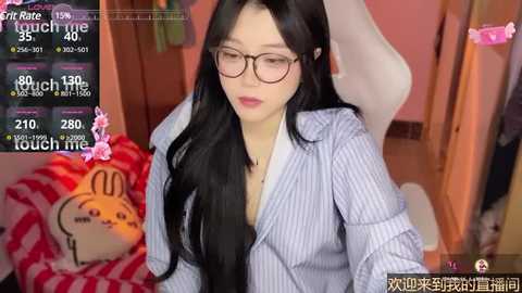 Media: A video of an East Asian woman with long black hair, glasses, and a pinstriped shirt, sitting on a white gaming chair in a cozy room with a pink wall and a stuffed bunny.