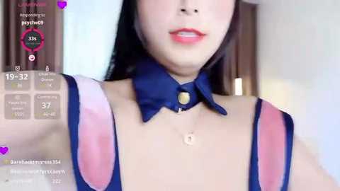 Media: Video of a young Asian woman with light skin and long black hair, wearing a revealing blue bunny costume with large, pink, heart-shaped cutouts.