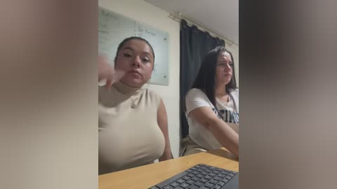 Media: Video of two Latina women in a classroom. One with medium breasts in a beige top, the other with large breasts in a white shirt. Both have dark hair and appear to be in their twenties.