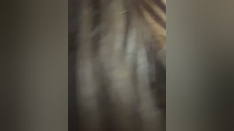 A blurry video depicting a person's torso, possibly a man, wearing a beige shirt with a visible necktie. The background is dark and indistinct, making it difficult to discern details.