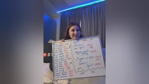 Media: A video of a woman holding a whiteboard with a list of tasks, set in a dimly lit room with blue LED lighting.