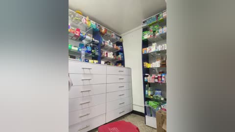 Media: A video of a neatly organized, white medicine cabinet with numerous bottles of various medications and toiletries, including toothpaste, deodorant, and shaving cream. The cabinet has multiple drawers and shelves.