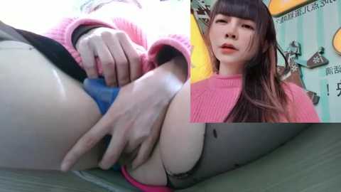 Media: Video of a young Asian woman with long brown hair, wearing a pink sweater, touching her exposed genitals. The background features a colorful, patterned wall with Japanese text.