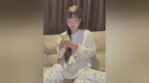 Media: Video of an Asian woman in pajamas reading a book on a beige sofa, with brown curtains in the background.