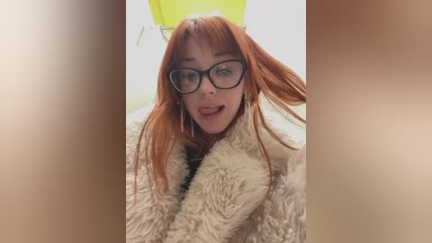 A video of a young woman with red hair, wearing large black glasses, a yellow headband, and a fluffy beige coat, her expression playful.