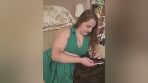 Media: Video of a plus-size woman in a green dress, sitting on a beige sofa, holding a smartphone, surrounded by floral and patterned decor.