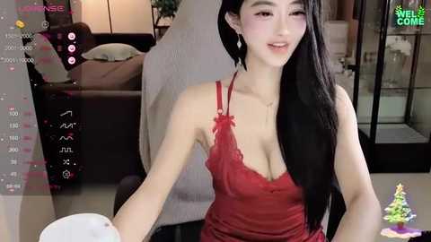 Media: Video of an East Asian woman with long black hair, fair skin, wearing a red lace camisole, smiling in a modern, warmly lit living room.