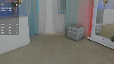 Media: Video of a modern, minimalist bridal suite with a plush silver ottoman, white curtains, and a large mirror. The background features a light grey carpet.