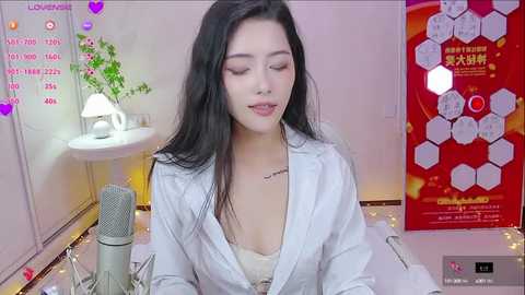 Media: A video of an East Asian woman with long black hair, wearing a white shirt, singing into a microphone, surrounded by pink heart decorations and a red poster.