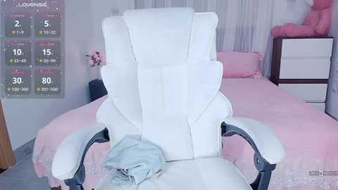 Video of a white gaming chair in a pink-themed bedroom with a bed, dresser, and a digital screen showing a score chart.