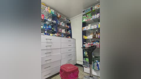 Media: Video of a well-lit, organized pharmacy with white shelves stocked with various medicines, a red stool, and a black scale on the floor.