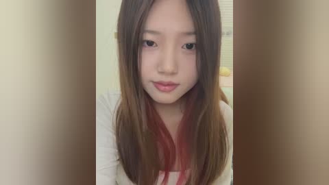 Media: Video of an East Asian woman with long, straight brown hair, fair skin, and light makeup. She wears a white shirt with a red bow. Background is blurred, showing a plain wall and window.