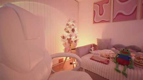 Media: Video of a cozy, pink-themed nursery with a white crib, a glowing Christmas tree, and a plush frog toy on a white blanket.