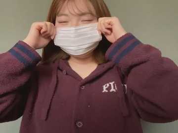 Media: Video of a young Asian woman with long, straight brown hair, wearing a maroon hoodie with \"PHI\" logo, adjusting a white face mask over her mouth and nose, indoors against a plain background.