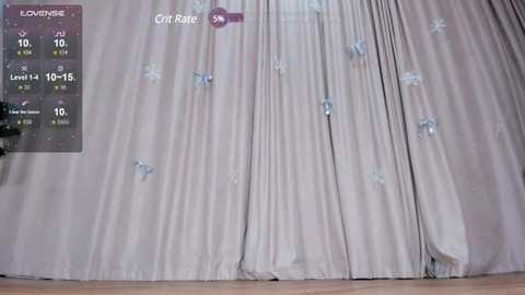 Video of a beige curtain with white butterflies, showing time and temperature in the top left corner. The curtain is slightly wrinkled, and the background is a light wood floor.