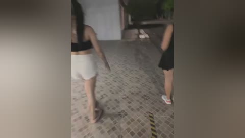 Media: Video of two women in workout gear, white shorts and black tops, running away from the camera on a tiled floor with a yellow caution stripe.