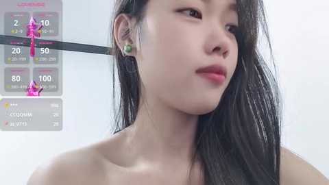 Media: A video of an Asian woman with long, straight black hair, wearing green stud earrings, in a white top, against a light background. The image includes a digital fitness tracker overlay.