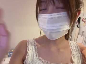 Media: Video of an Asian woman in a white lace tank top and surgical mask, eyes closed, in a dimly lit room with blurred background.