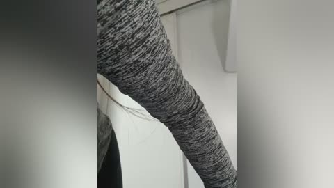 Media: A close-up video of a person's legs in grey, textured leggings, standing against a white wall. The image focuses on the lower body, highlighting the fabric's texture and the person's stance.