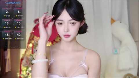 Media: Video of a young East Asian woman with pale skin, dark hair, and a slender build, wearing a white camisole, adjusting her hair in a bedroom with plush toys and a red blanket.