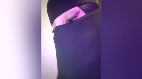 Media: Video of a person in a black hoodie, partially obscured by the hood, with a purple light illuminating the right side of their face.