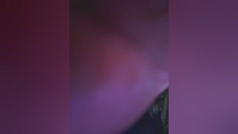 Media: A video with a blurred, indistinct figure partially obscured by a pink and purple gradient, likely in a dimly lit room. The image's focus is unclear, making it difficult to discern details or identify the subject.