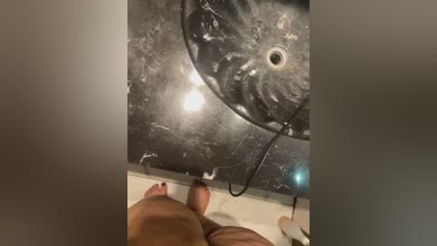 Video of a large, dark, circular, possibly metallic object with a hole and reflective surface, possibly an industrial piece of equipment, seen from below.