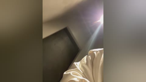 Media: Video of a close-up of a white pillow and a black phone, slightly blurred, with lens flare in the top right.