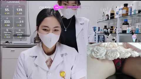 Video of an Asian woman in a lab coat and mask, with a digital display showing COVID-19 stats in the background.