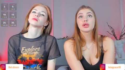 Video of two fair-skinned women with red hair and light makeup, one wearing a sheer black top, the other in a black lace bra, both looking at the camera with a slightly pouty expression.